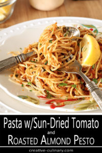 Fork Twirled with Pasta with Sun-Dried Tomato and Roasted Almond Pesto on White Decorated Plate