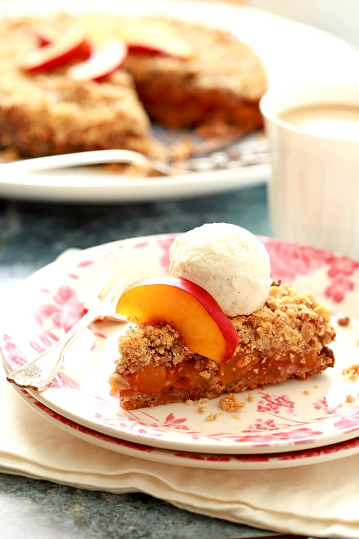 Slice of Fresh Peach Cobbler with Two Crusts on a White Plate with Pink Decorations