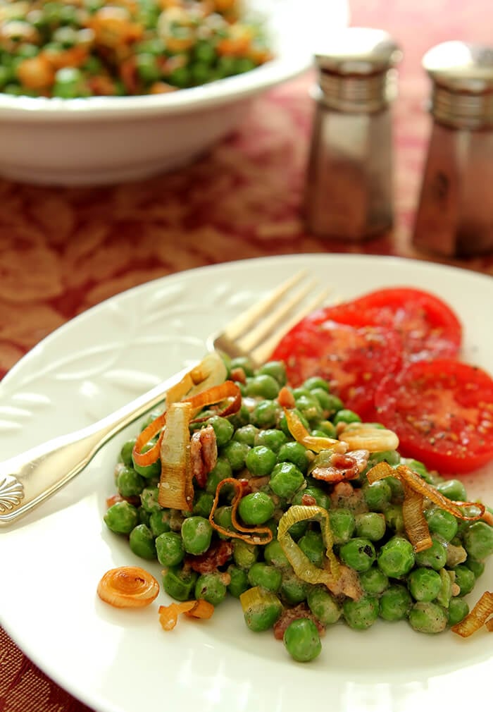 Peas with Bacon and Leeks Served on a White Plate with Fresh Tomato Slices