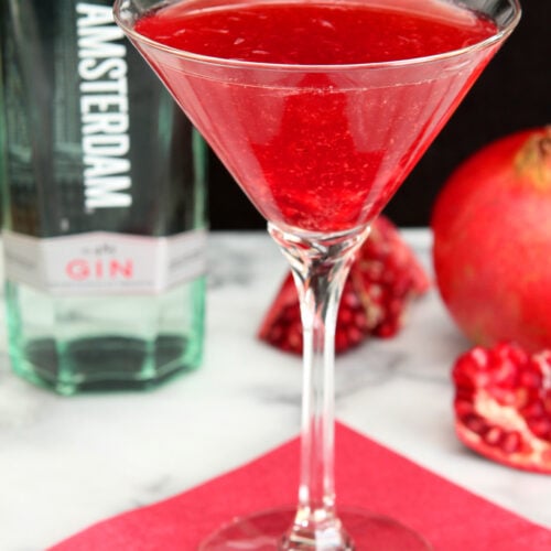 Martini glass with red gin and pomegranate cocktail.