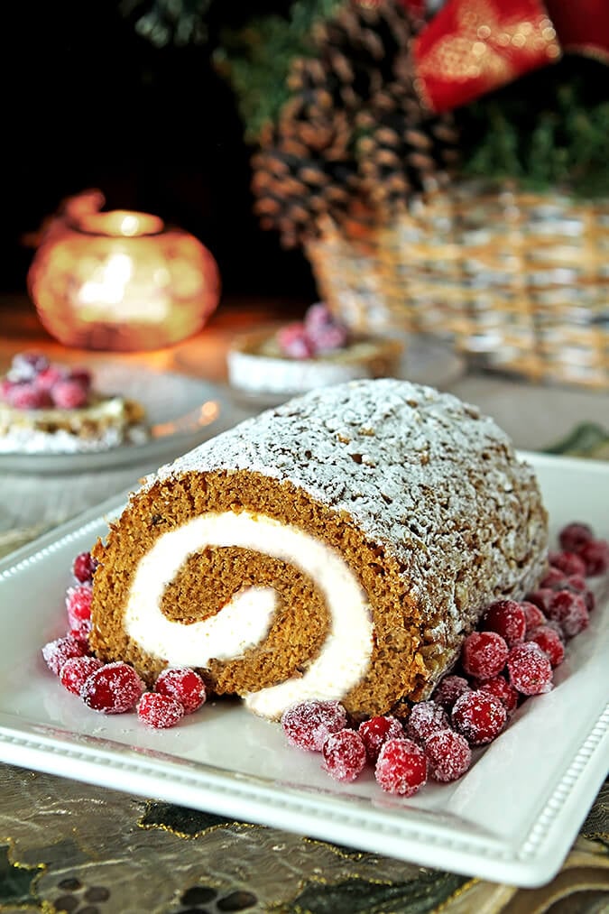 Pumpkin Roll with Cream Cheese Filling on a White Serving Plate and Garnished with Sugared Cranberries