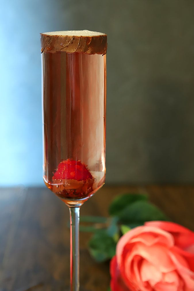 Sparkling Rosé Wine is poured int glasses decorated with chocolate and fresh raspberries.