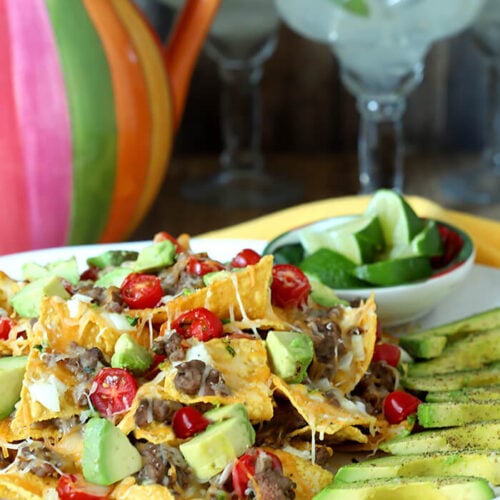 Plate of Refried Bean and Beef Nachos with Lime Wedges