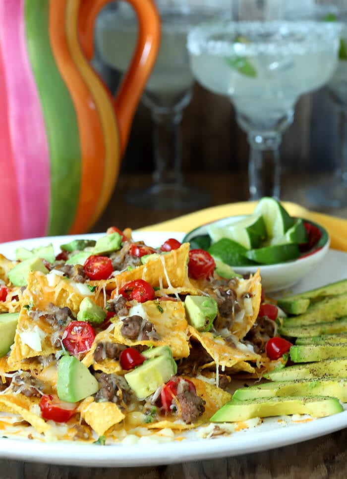 Plate of Refried Bean and Beef Nachos with Lime Wedges