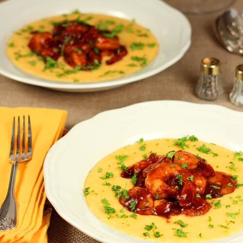 Barbecue Shrimp with Cheese Grits Served in a White Bowl and Garnished with Parsley