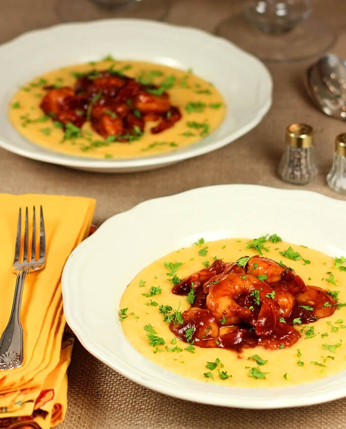 Barbecue Shrimp with Cheese Grits Served in a White Bowl and Garnished with Parsley