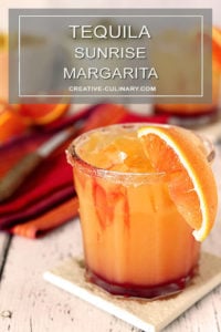 Tequila Sunrise Margarita Garnished with a Sugar Rim and an Orange Wedge