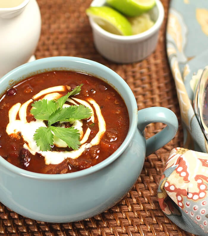 Three Bean Chili in a Blue Crock with Sour Cream and Lime Garnish